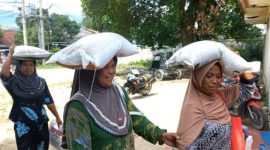 Warga usung satu sak beras di kepala.