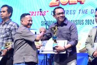 Camat Situbondo Jupri Setyo Utomo, S.STP saat menerima piala penghargaan dari Bupati Situbondo Karna Siswandi. (Foto. Arief Yuda)